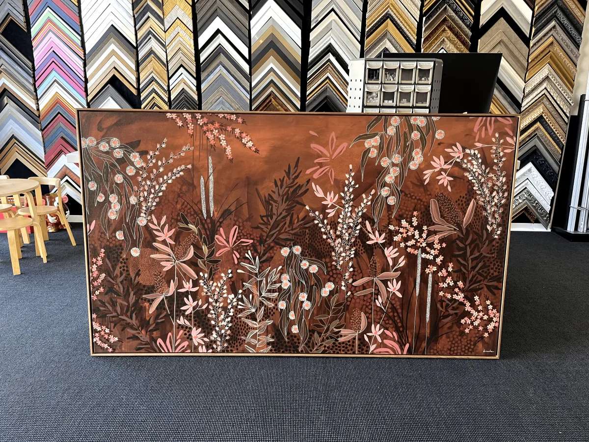 Float-framed canvas in front of the moulding sample wall in the Norma Road showroom